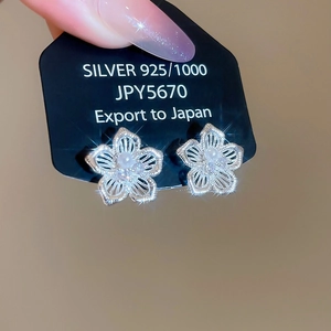 Gros plan de boucles d'oreilles fleur en argent 925 avec perles sur carte noire