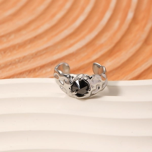 Irregular silver textured ring with black faceted gemstone on a white minimalist display