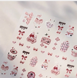 Detail of winter theme nail stickers featuring red snowmen, bows, and plaid heart patterns