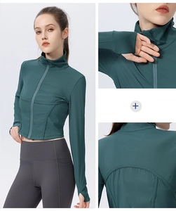 Detail view of teal yoga jacket featuring thumbholes, zip-up collar and ribbed fabric texture