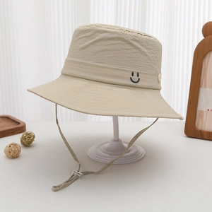 Detail of adjustable chin strap and smiley embroidery on cream polyester sun hat