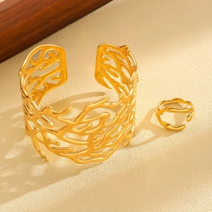 Detailed macro view of golden coral-patterned open cuff bracelet and matching ring set