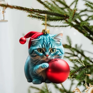 Cute acrylic blue cat ornament with red Christmas hat and ball on a festive tree branch