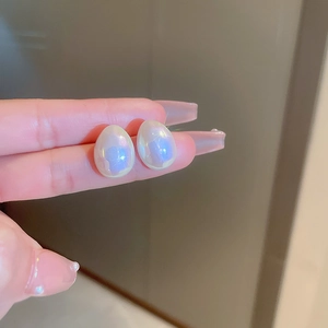 Gros plan sur des boucles d'oreilles perles avec reflets irisés bleu-violet