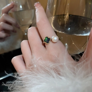 Nahaufnahme von vergoldetem verstellbarem Ring mit Kleeblatt und Perle auf Luxushintergrund
