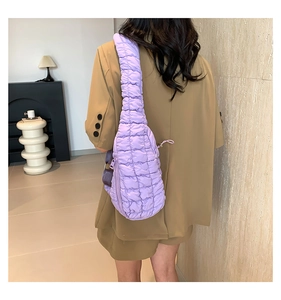 Détail du sac nuage matelassé violet porté sur un blazer kaki dans un décor moderne