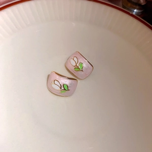 Dettaglio degli orecchini a tulipano in smalto rosa con bordo dorato in un piatto