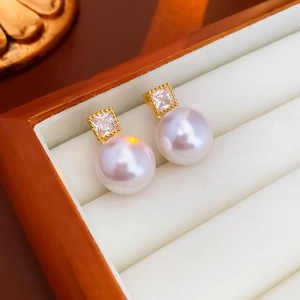 Macro shot of elegant white pearl earrings with gold-plated zircon in a jewelry box