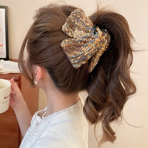 Gros plan d'une pince à cheveux en tweed avec nœud portée par un mannequin femme