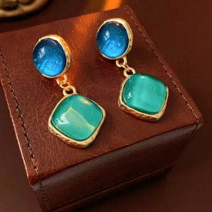 Détail de boucles d'oreilles vintage avec pierres bleu-vert et monture en métal doré