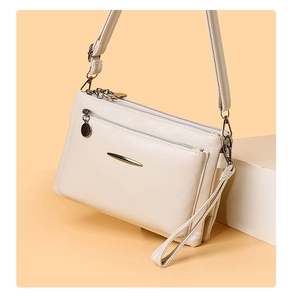 Detailed close-up of cream PU leather shoulder bag with metallic trim and detachable straps