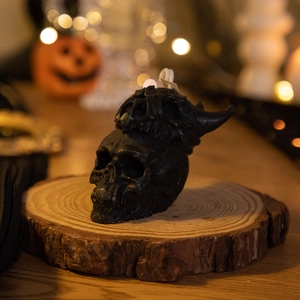 Macro shot of a black skull candle with horn details on a wooden base for Halloween decor