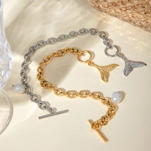 Detailed shot of 18k gold and silver fishtail bracelets with pearls and OT toggle clasps