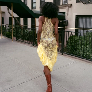Vue arrière d'une robe jaune sans manches en dentelle avec ourlet à volants sexy