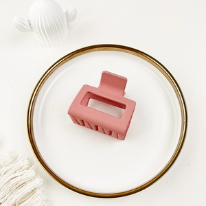 Detailed top view of a matte pink shark hair claw clip on a white decorative plate
