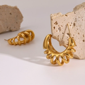 Macro shot of 18k gold plated hollow C-shape earrings displayed on a natural raw stone