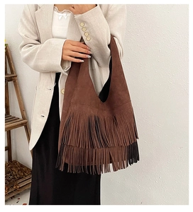 Detail of a dark brown suede shoulder bag with dense fringe accents and retro style