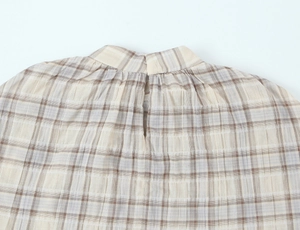 Detail view of plaid seersucker crop top featuring khaki texture and back button closure