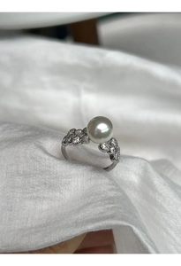 Macro shot of silver lace ring with white pearl and diamonds on white cloth