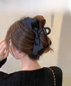 Detailed back view of a black satin bow hair claw clip styled on a woman's hair