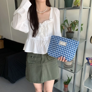 Détail de la pochette tissée à carreaux bleu et blanc tenue par un mannequin au quotidien