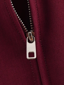 Detailed close-up of a burgundy twill jacket featuring a silver metal zipper closure