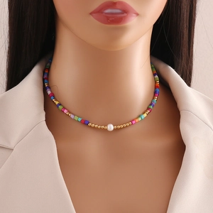 Detail of colorful beaded necklace featuring a white pearl and gold accents on a model