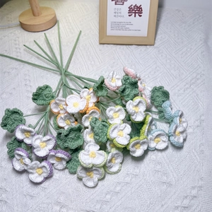 Handmade crochet pansy bouquet in colorful cotton yarn with green stems on lace cloth