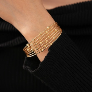 Détail du bracelet spirale multicouche en métal doré avec des perles gravées