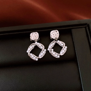 Detailed shot of square geometric earrings with silver metal and small white pearls