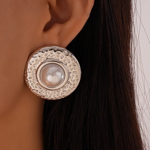 Detail of silver textured hammered hoop earring with large white pearl on model