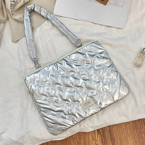 Close-up of silver quilted laptop sleeve with bow texture and elegant brand tag details