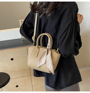 Detail view of tan lychee grain bucket bag with decorative silk scarf and thin leather strap