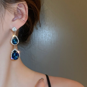 Dettaglio di orecchini a goccia con cristalli blu e montatura in argento su modella