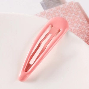Close-up of pink lacquer drop hair clip for girls on a white textured display base