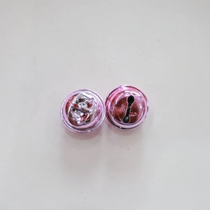 Detailed macro view of two pink metal bells with hanging loops and bottom slots