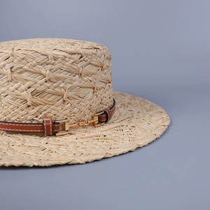 Handwoven raffia boater hat with flat top and brown leather band featuring gold buckle