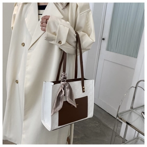 Contrast color tote bag with silk scarf accessory worn with an elegant beige coat