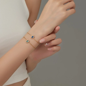 Elegant gold chain bracelet with teardrop-shaped blue and teal zircon gemstones on model