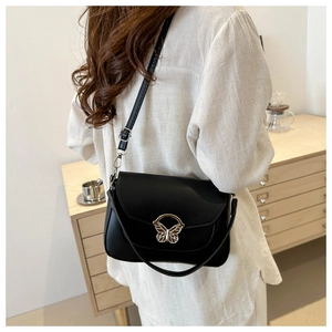 Detail shot of the elegant butterfly metal clasp on the black leather crossbody bag