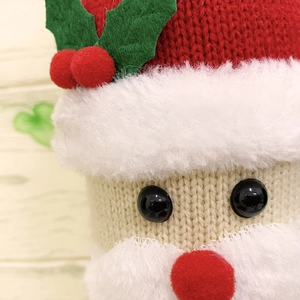 Close-up of Santa Claus wine bottle cover with red knit fabric and plush beard detail