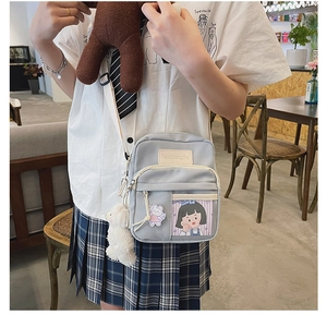 Détail du sac bandoulière en toile bleu clair avec poche cartoon et breloque mouton