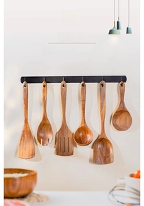 6-piece teak wood cooking utensil set with black metal hanging rack on a white wall
