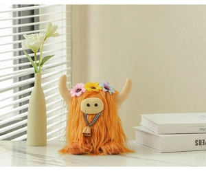 Detail of Scottish Highland cow plush with colorful flower crown and bell ribbon on marble