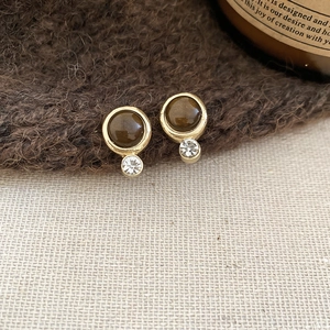 Close-up of vintage round tiger eye stone earrings with golden base and zircon detail