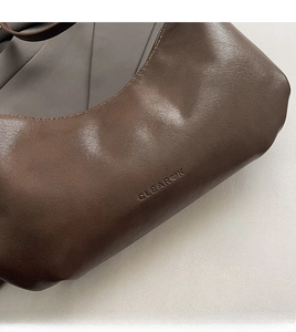 Close-up of the embossed logo on the premium dark brown leather underarm handbag