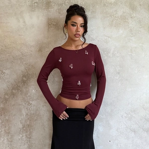 Close-up of slim-fit burgundy long sleeve top with sparkling crystal embellishments