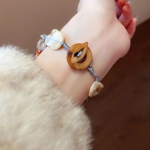 Close-up of handmade shell bead bracelet with irregular stones and brown button clasp