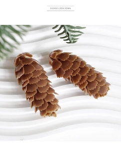 Macro shot of two brown artificial pine cones with layered textures on a white modern base