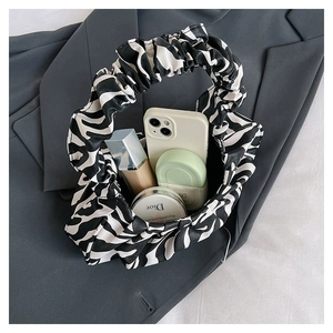 Detail view of cloud shape shoulder bag with zebra print pattern on a grey suit jacket